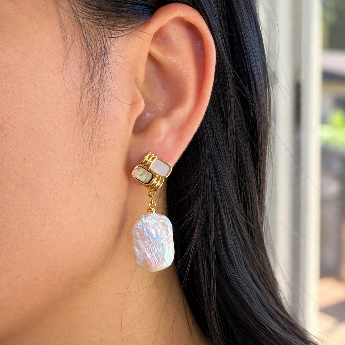 Gold baroque pearl drop earrings, close-up worn on model