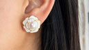 Gold camellia flower pearl stud earring worn on model